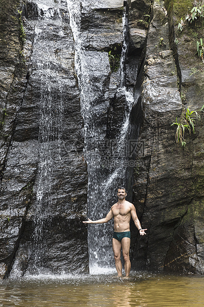 巴西里约热内卢蒂华卡森林瀑布前张开双臂的成年男子肖像图片