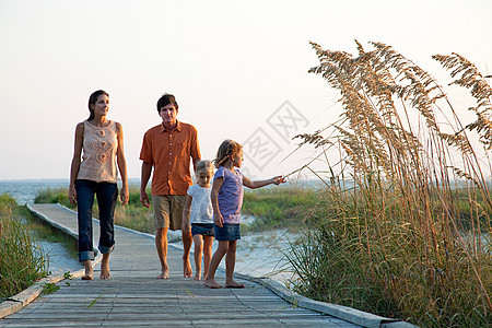 在海滩走道上散步的一家人图片