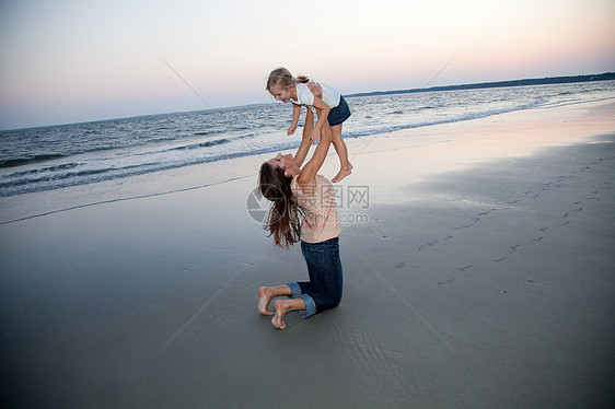 母亲在海滩上举起女儿图片