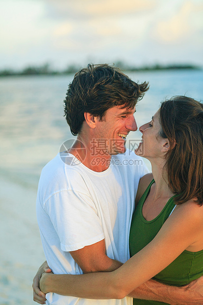 微笑的情侣拥抱在海滩上图片