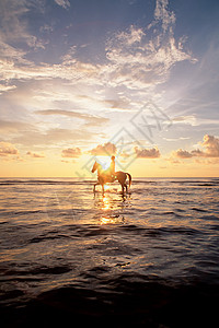 日落时在海上骑马的人背景图片