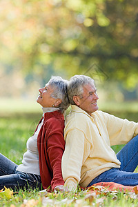 一对老夫妇背靠背地坐在公园里图片