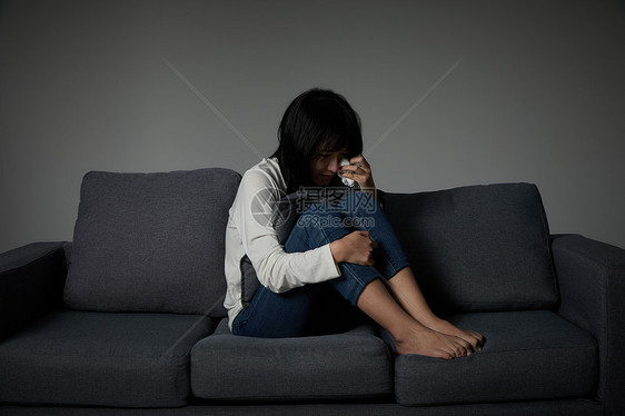 年轻女性坐在沙发上哭泣图片