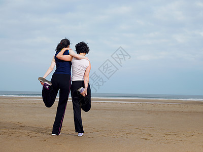 两个年轻的女人在海滩上伸展身体图片