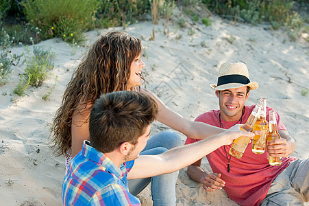 坐在沙滩上喝啤酒的年轻人图片