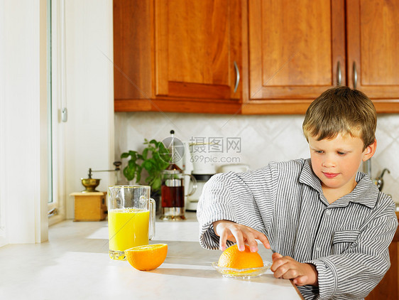 小男孩在厨房里做橙汁图片