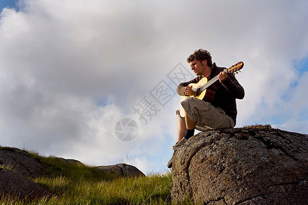 在风景区弹吉他的年轻人图片