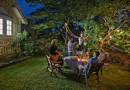 夜晚花园中举办家庭聚会的快乐一家人背景