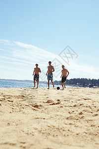 在海滩上踢足球的男人图片
