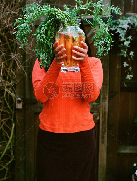 拿着一瓶胡萝卜的女人图片