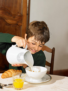 男孩把牛奶倒在谷类食品上图片