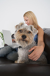 玩着笔记本电脑和宠物狗的女人图片