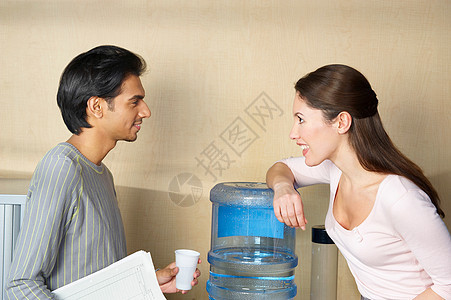 在饮水机旁聊天的男女图片