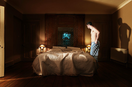 穿着睡衣的男人站在床边图片