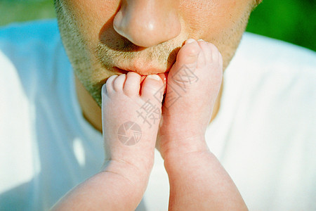 爸爸亲吻婴儿的脚背景图片