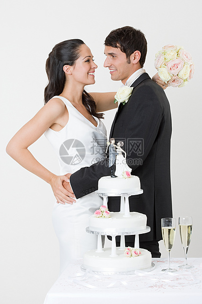 站在结婚蛋糕旁边的新婚夫妇图片