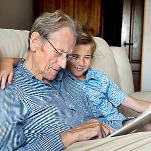 在看数字平板电脑的祖父和孙子图片