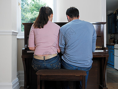弹钢琴的年轻夫妇背景图片