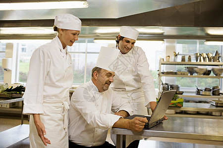 三个厨师看着笔记本电脑图片