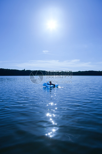 湖中带着充气海豚游泳的男孩图片