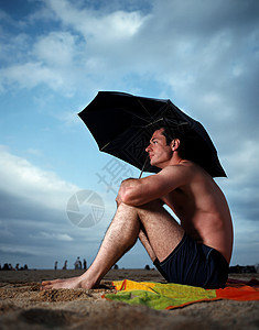 沙滩上撑伞的男人图片