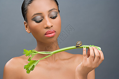 女人看着一根芹菜上的蜗牛图片