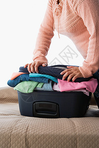 一个女人压着一个装满衣服的手提箱图片