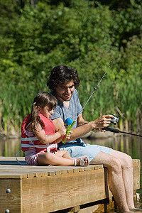 父亲节日父亲和女儿在码头钓鱼背景