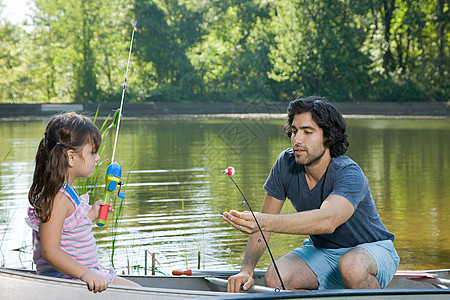 父亲和女儿带着鱼竿在划艇上图片