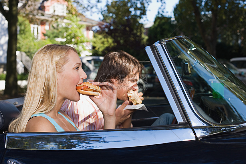 夫妇在敞篷车里吃汉堡