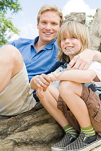 男孩和父亲坐在树干上图片
