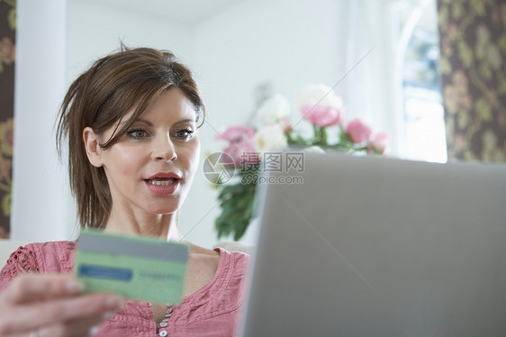 拿着信用卡的女人用笔记本电脑里图片