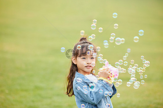 小女孩草地上玩泡泡机图片