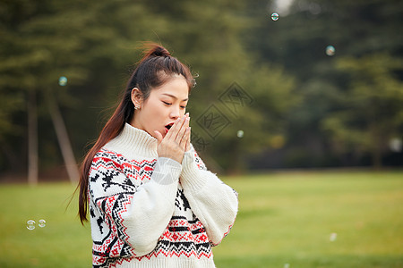 年轻女性站在草地上哈手图片