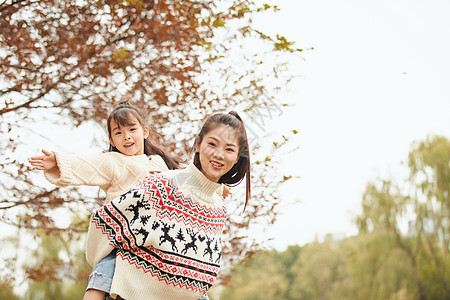 年轻妈妈背着女儿玩耍图片