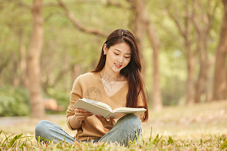 年轻女性坐在草地上看书图片