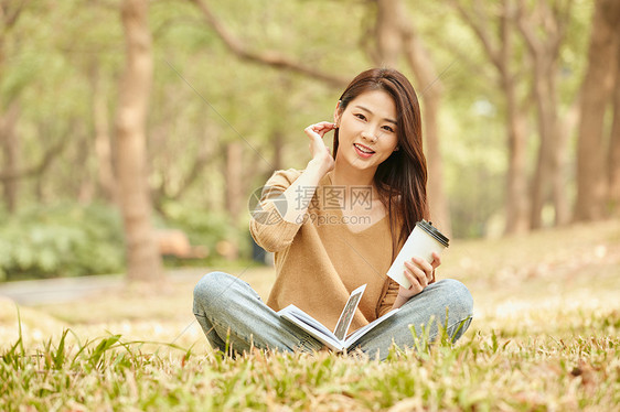 年轻女性草地上看书喝咖啡图片