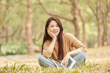 年轻女性坐在草地上看书图片