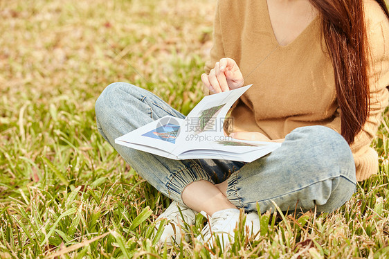 年轻女性坐在草地上看书图片