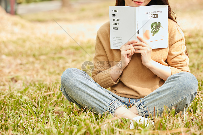 年轻女性坐在草地上看书图片