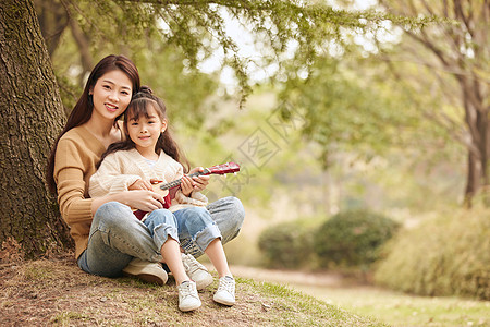 母女坐在树下弹尤克里里图片