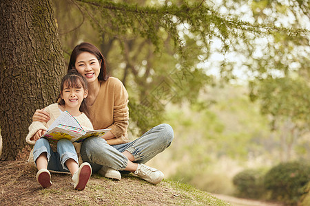 世界旅游温馨母女坐在树下读书背景