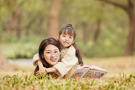 母女趴在草地上读书高清图片