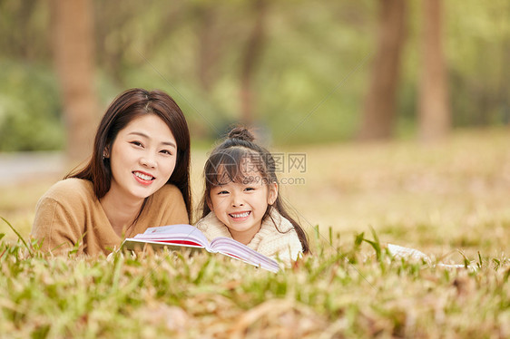母女趴在草地上读书图片