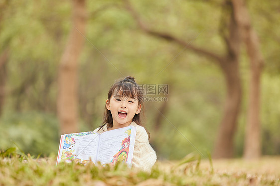 小女孩趴在草地上看童话故事图片