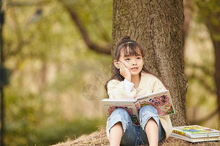 小女孩坐在树下看童话故事图片