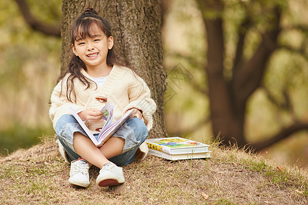 小女孩坐在树下看童话故事图片