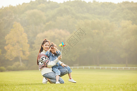 温馨母女坐在草坪玩风车图片