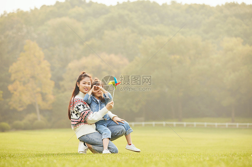 温馨母女坐在草坪玩风车图片