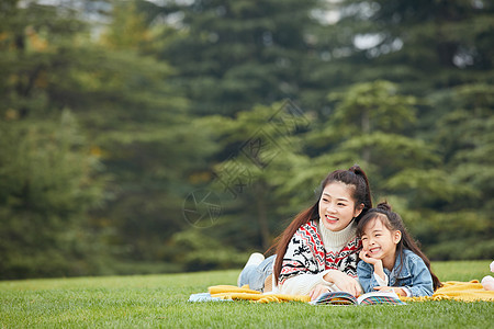 母女趴在草地上阅读背景图片